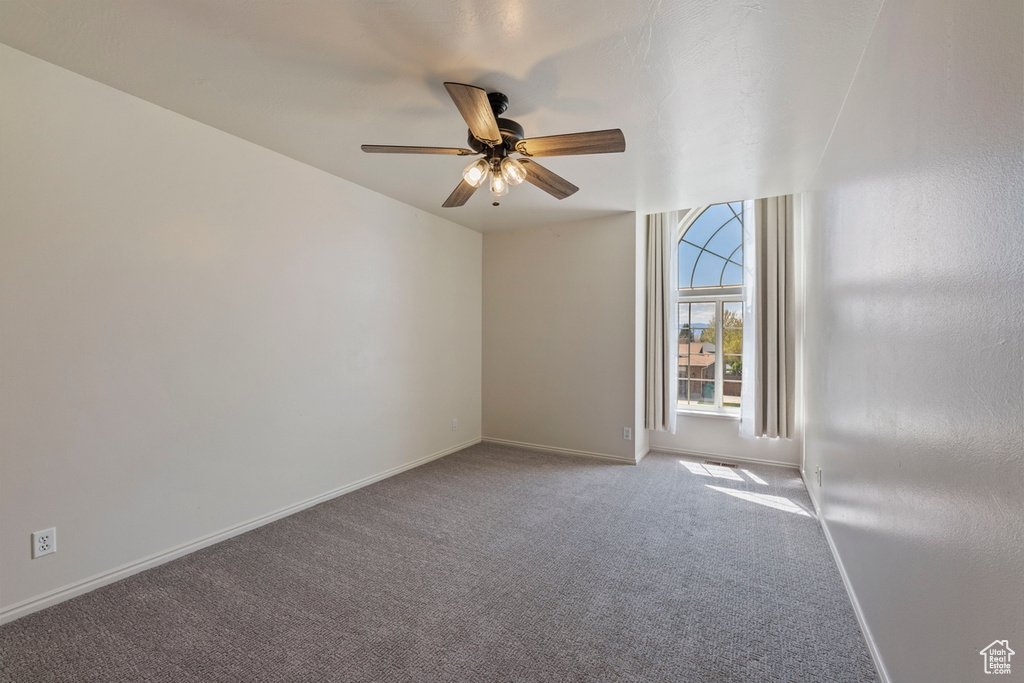 Carpeted spare room with baseboards and ceiling fan