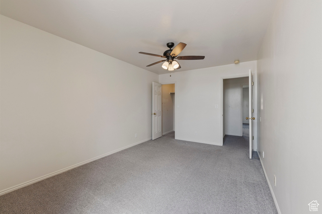 Unfurnished bedroom featuring baseboards, ceiling fan, and light colored carpet