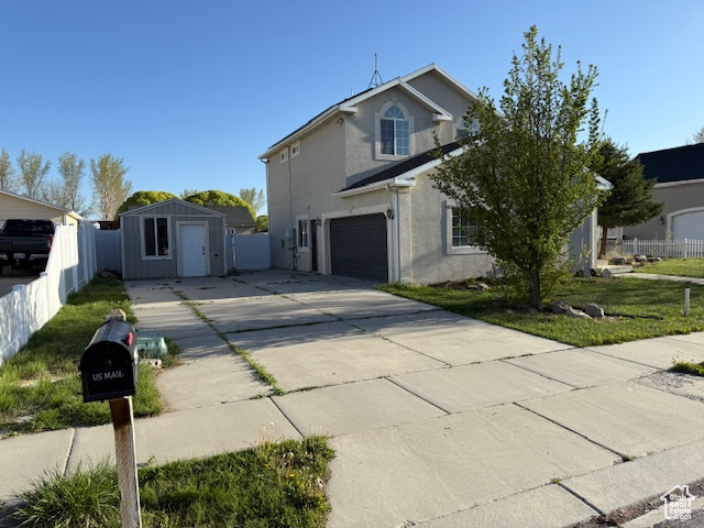 Traditional-style house featuring an attached garage, stucco siding, driveway, and fence