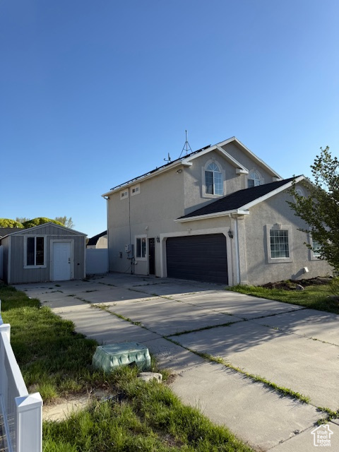 View of property exterior featuring an attached garage, stucco siding, an outbuilding, and concrete driveway