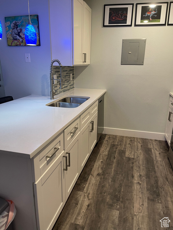 Kitchen with dark wood-style flooring, baseboards, light countertops, electric panel, and a sink