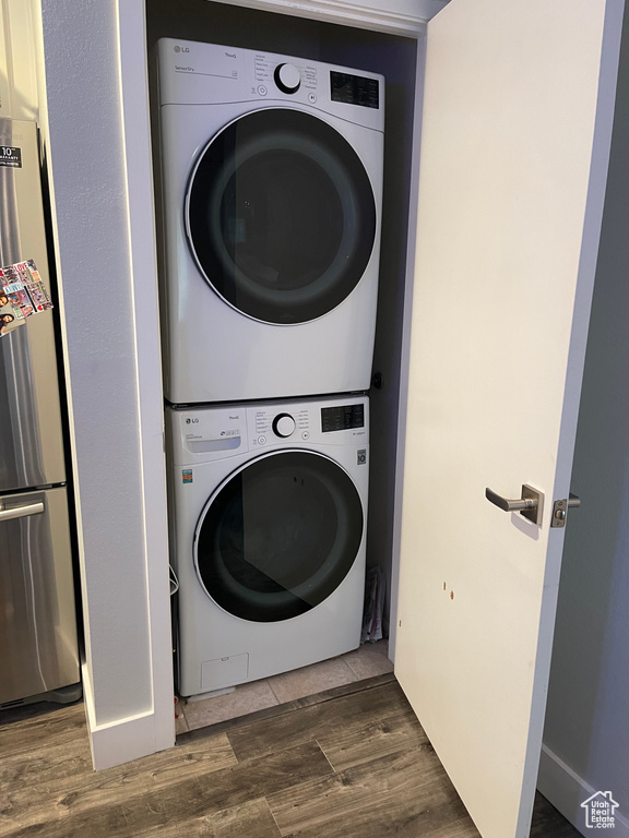 Washroom with wood finished floors, laundry area, and stacked washer / drying machine