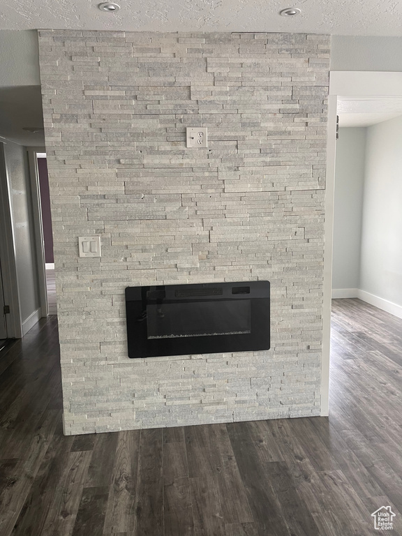 Room details featuring baseboards, a fireplace, a textured ceiling, and wood finished floors