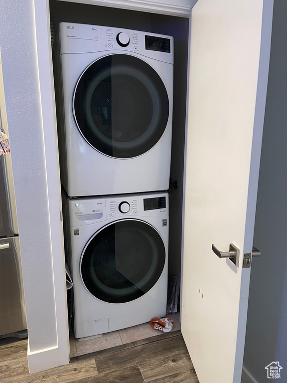 Laundry area featuring stacked washer / drying machine, wood finished floors, and laundry area