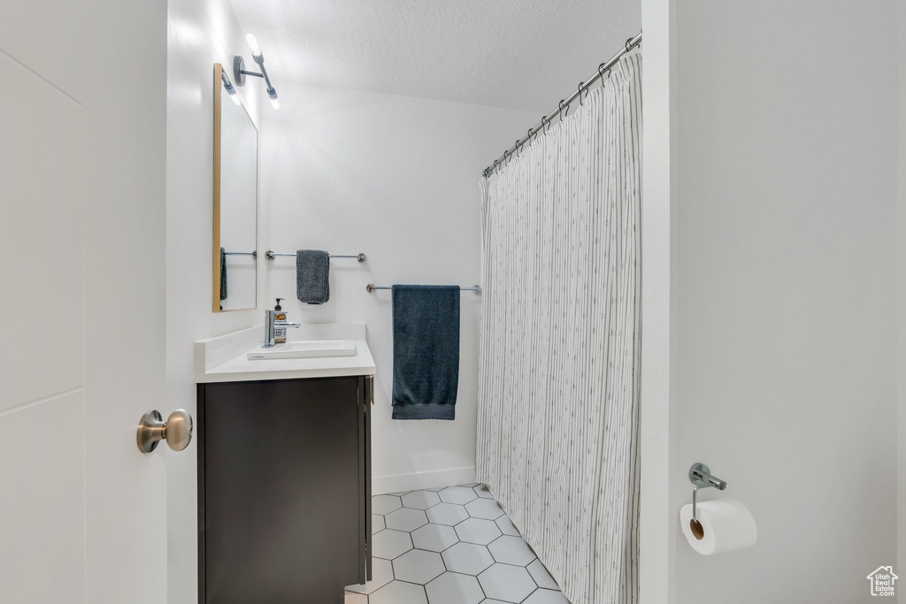 Full bath featuring vanity, a textured ceiling, a shower with shower curtain, and tile patterned flooring