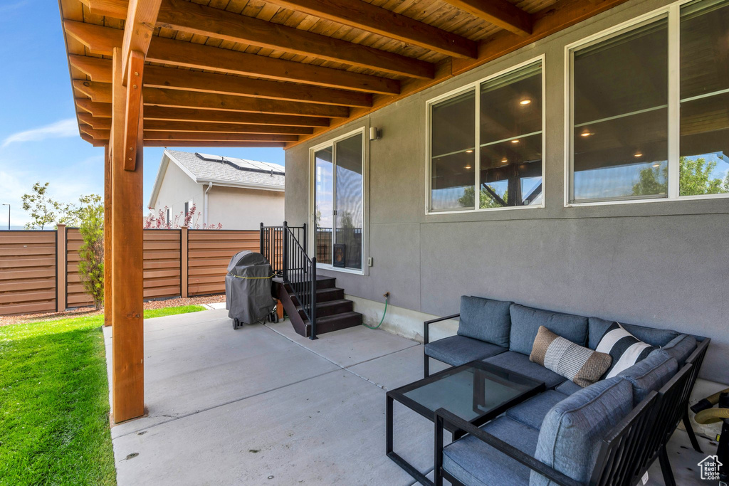 View of patio with an outdoor hangout area, fence, and grilling area