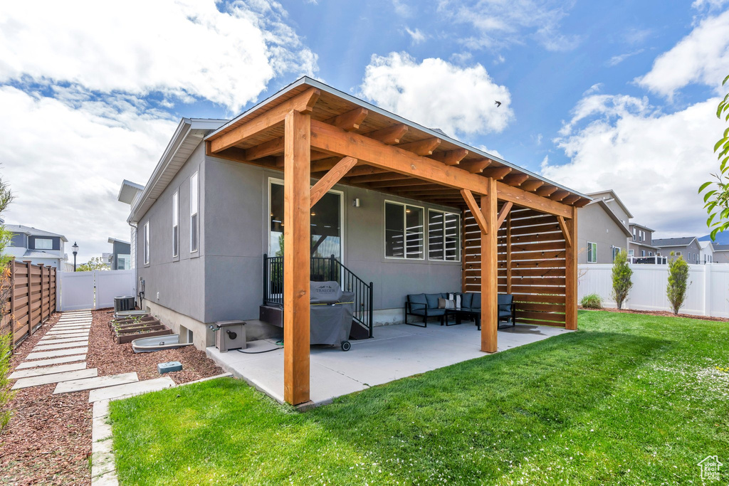 Rear view of house with stucco siding, a fenced backyard, cooling unit, a patio area, and a lawn