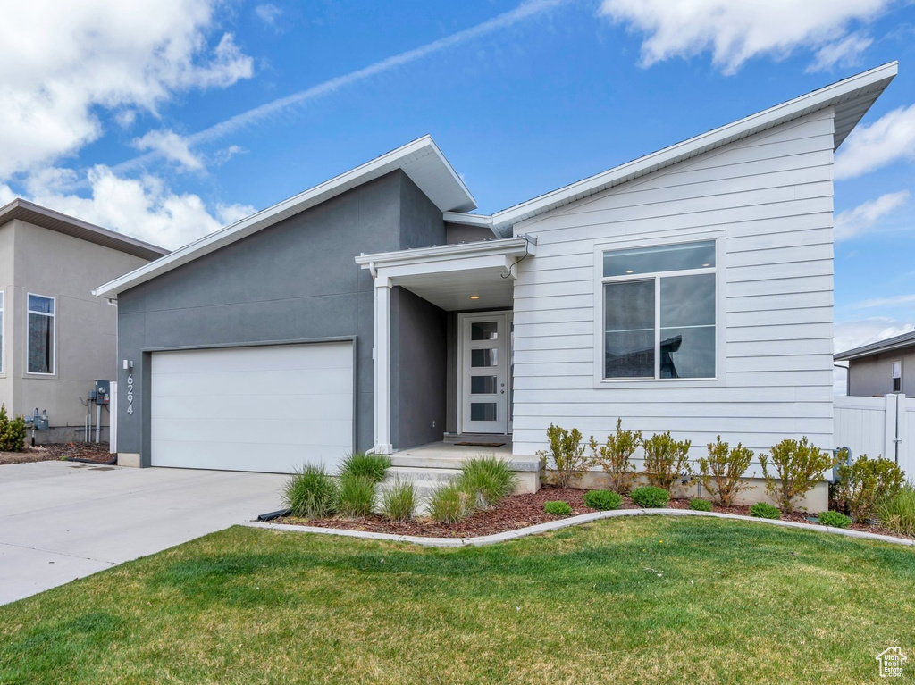 View of front of property with a garage, a front lawn, fence, and concrete driveway