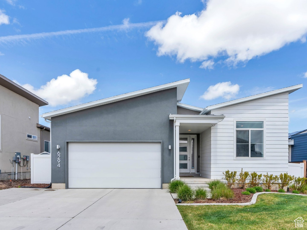 Modern home with a garage, fence, driveway, and a front yard