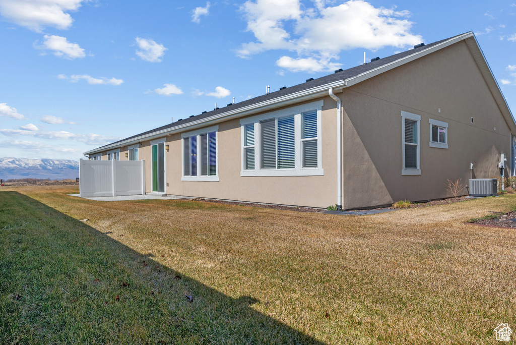 Rear view of house featuring a lawn, stucco siding, and cooling unit