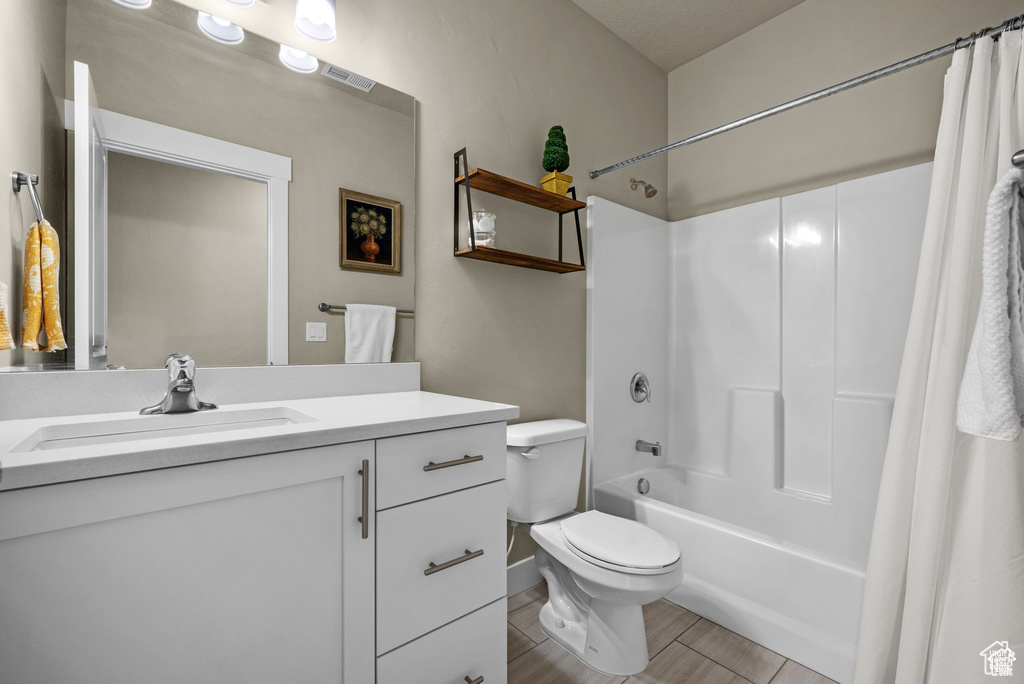 Full bathroom with vanity, visible vents, toilet, baseboards, and shower / bath combo