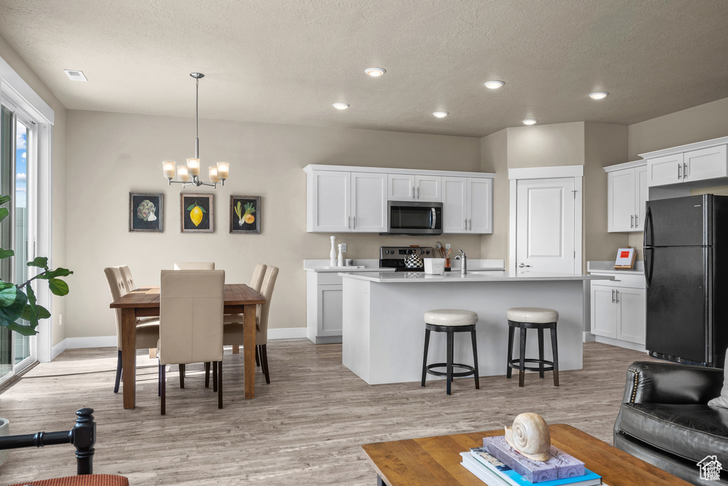 Kitchen featuring a kitchen breakfast bar, light countertops, white cabinets, a chandelier, and stainless steel appliances