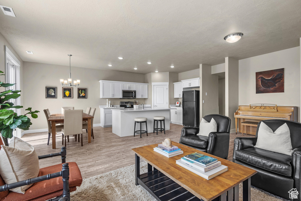 Living room featuring an inviting chandelier, recessed lighting, baseboards, light wood-type flooring, and visible vents