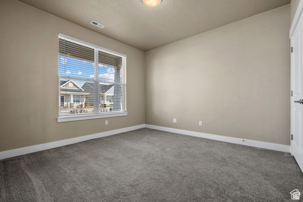 Carpeted spare room featuring visible vents and baseboards