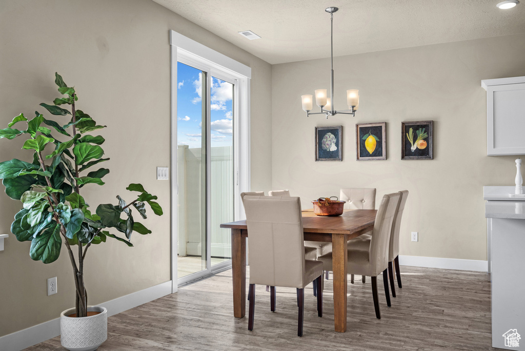 Dining space with baseboards, a chandelier, and wood finished floors