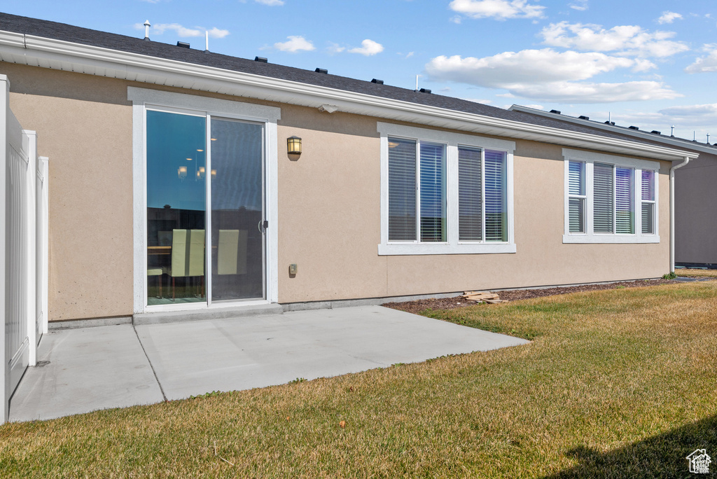 Rear view of property with a lawn, a patio area, and stucco siding