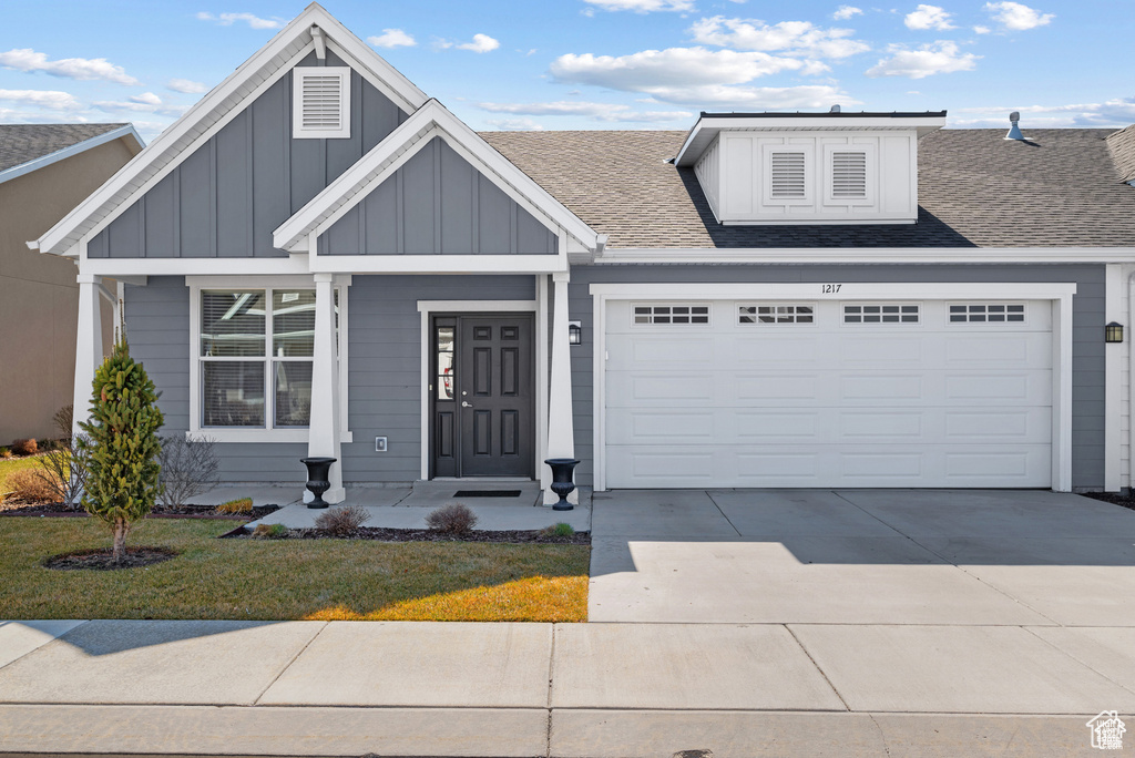 View of front of home featuring a garage, board and batten siding, roof with shingles, and driveway
