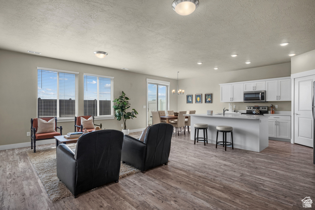 Living area with baseboards, dark wood-style floors, recessed lighting, a textured ceiling, and a notable chandelier