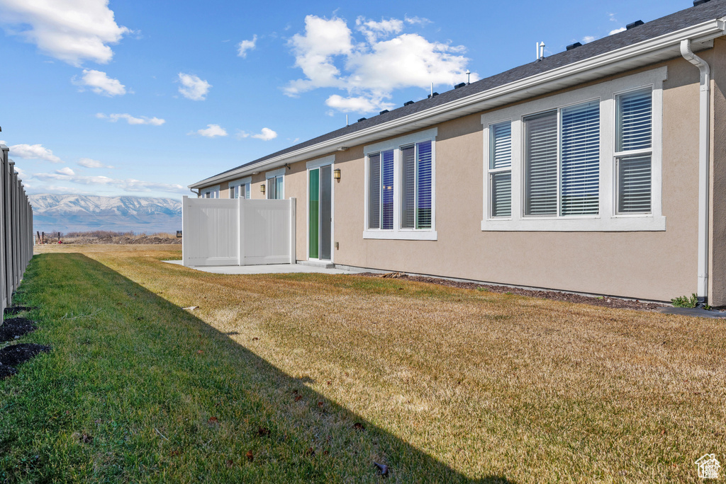 Back of property featuring a lawn, fence, and stucco siding