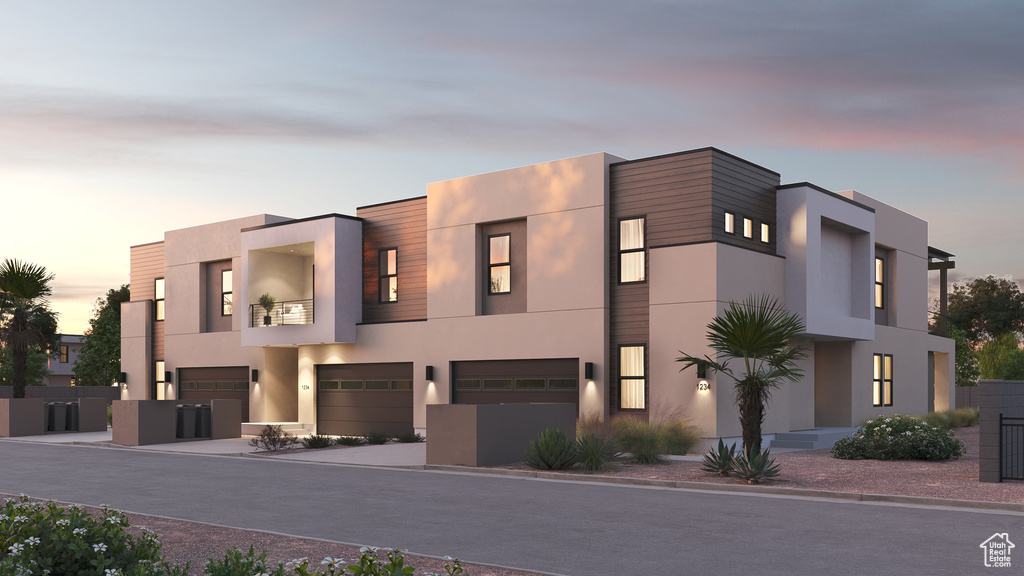 View of front of home with an attached garage, stucco siding, and a balcony