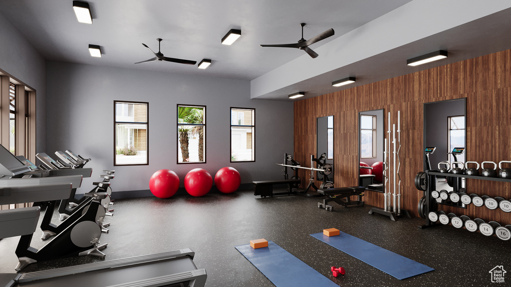 Gym featuring baseboards, wooden walls, ceiling fan, and a wealth of natural light