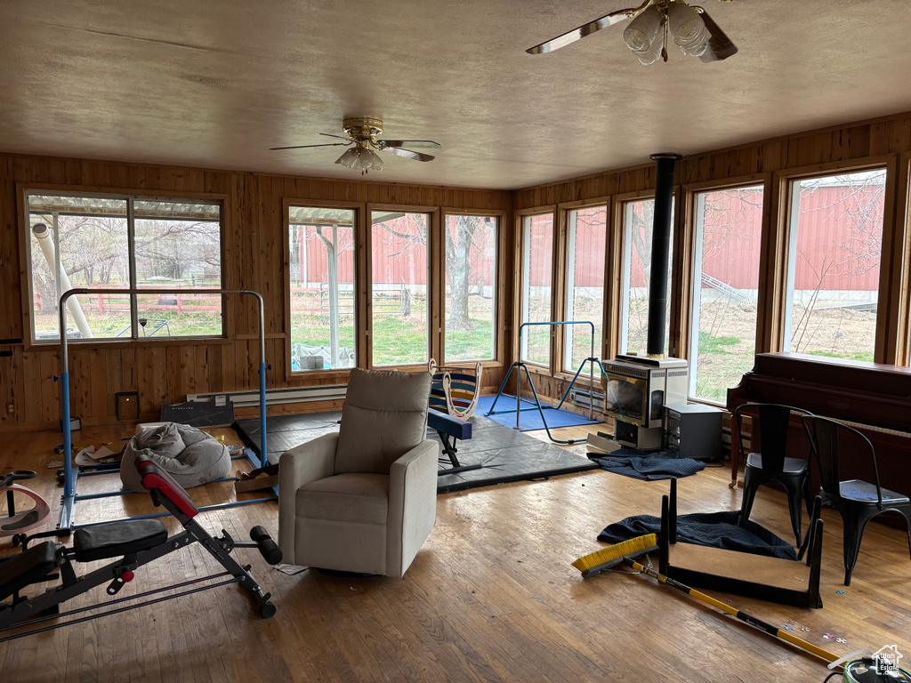 Sunroom / solarium featuring wood walls, wood finished floors, and a wood stove