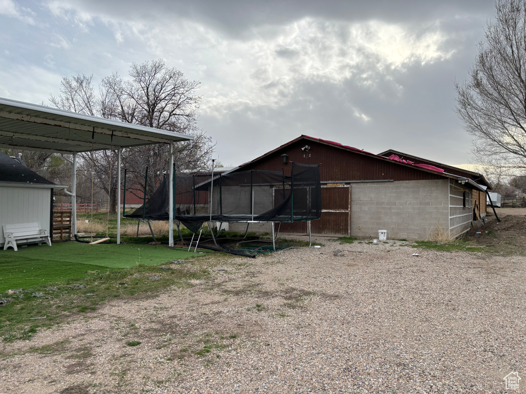 Exterior space featuring concrete block siding and a trampoline