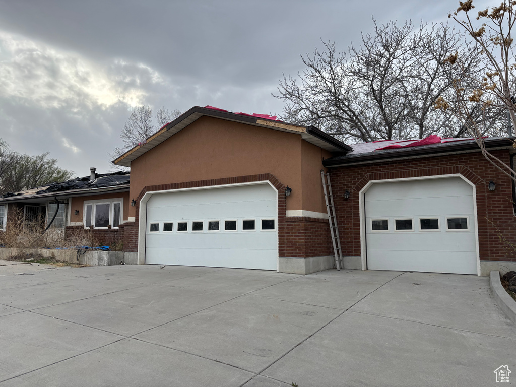 Single story home with concrete driveway, brick siding, stucco siding, and a garage