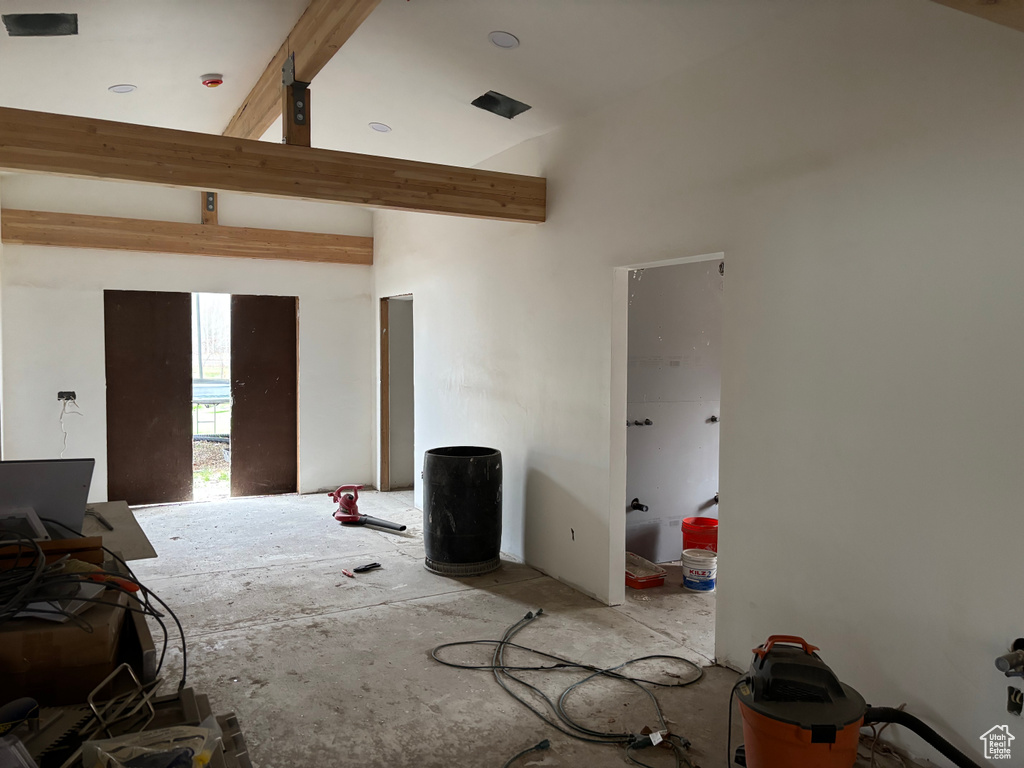 Unfurnished living room featuring beamed ceiling and high vaulted ceiling