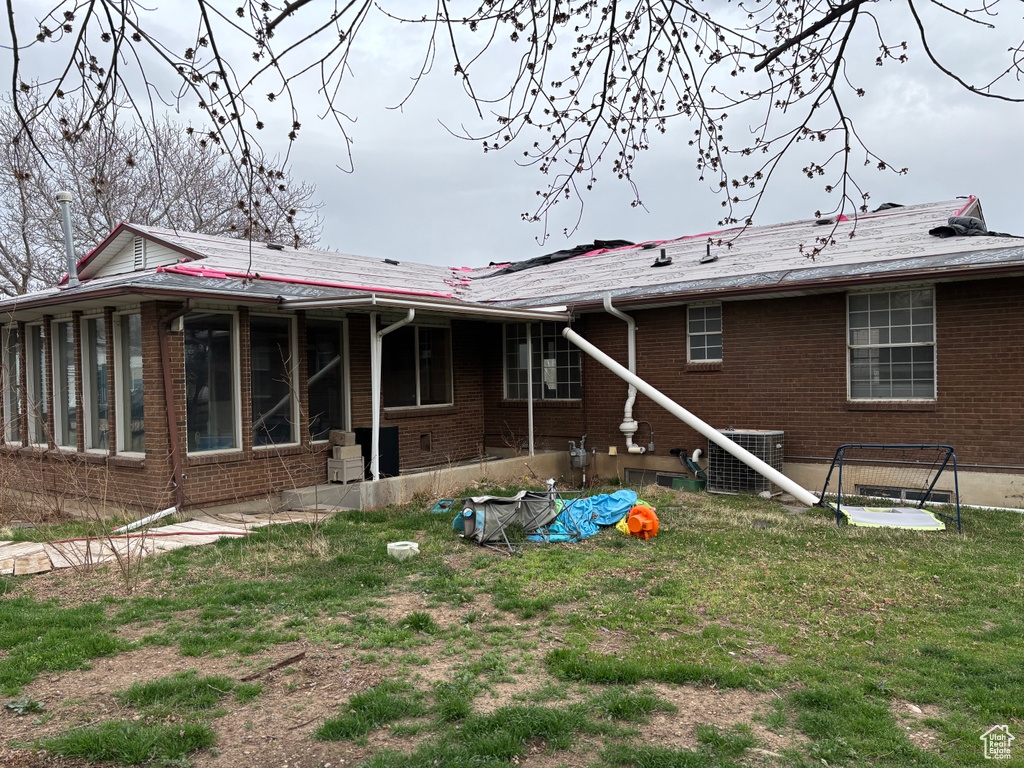 Back of house with a sunroom, central AC, and brick siding