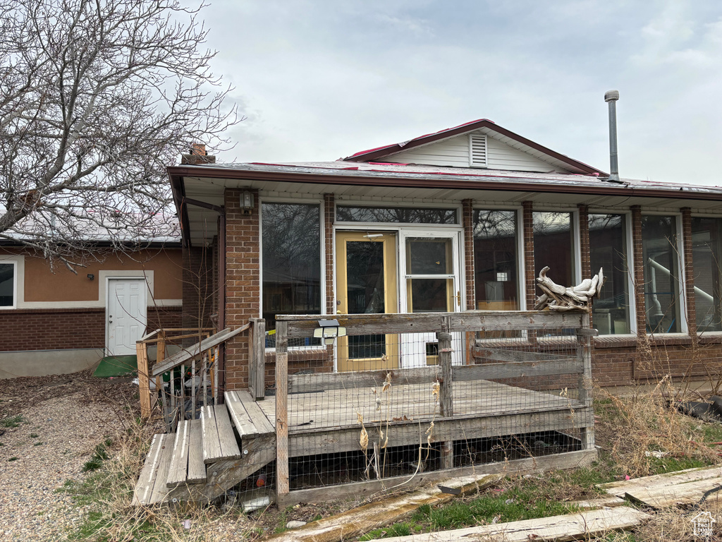 View of front of house featuring a sunroom, a deck, and brick siding