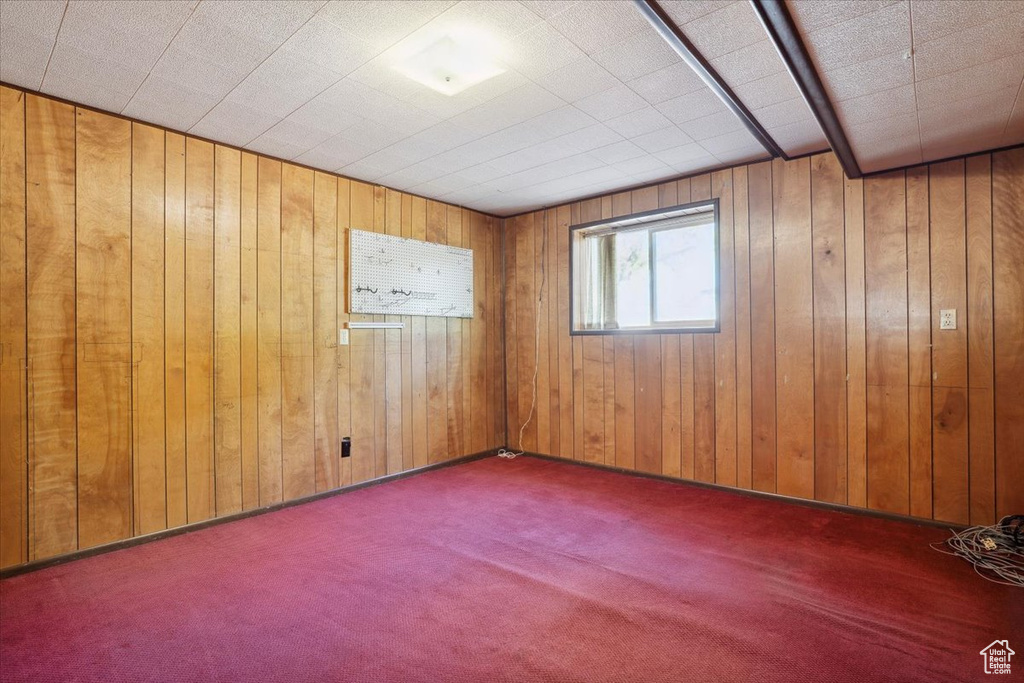 Carpeted spare room featuring wood walls