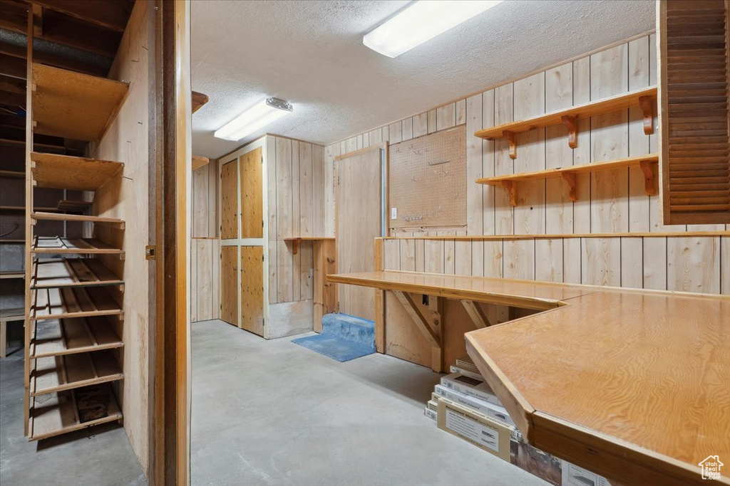 Basement with wooden walls and a textured ceiling