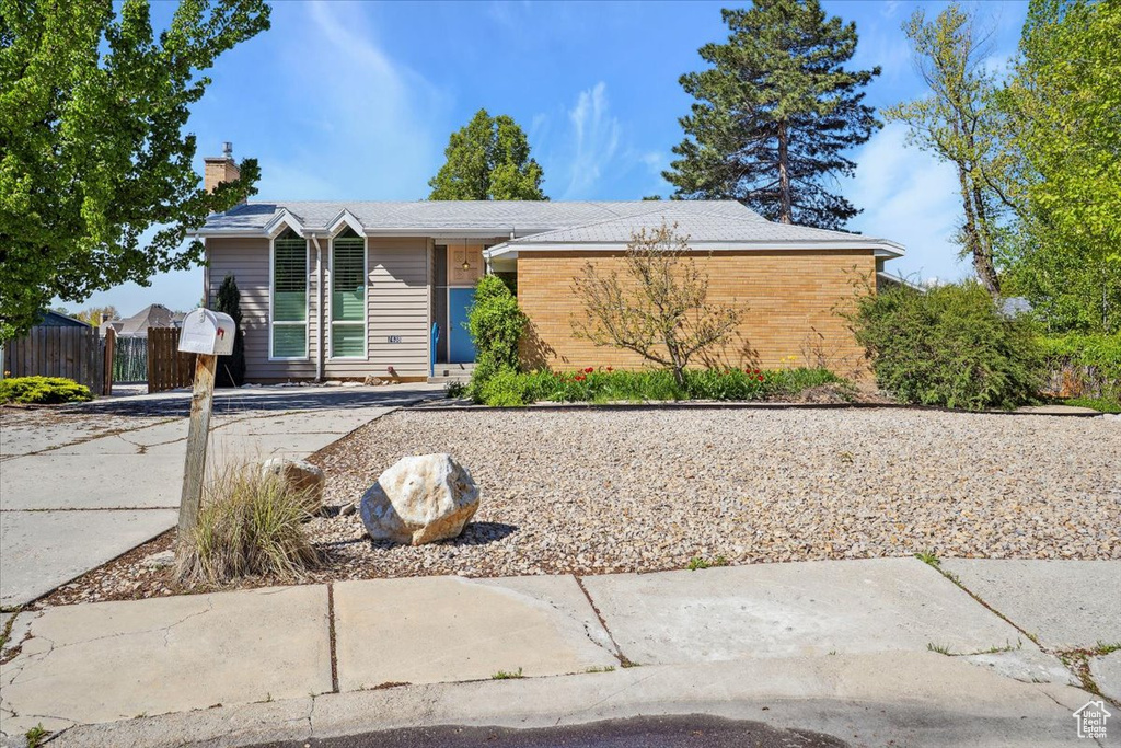 View of front of property with brick siding, fence, and a chimney