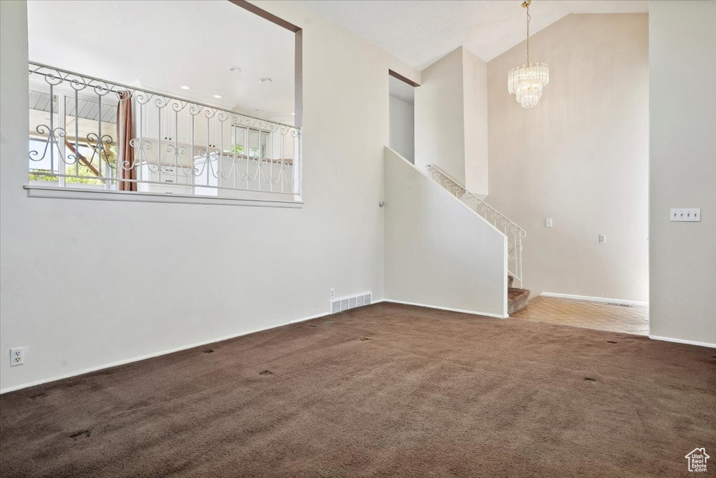 Unfurnished living room with visible vents, stairs, baseboards, carpet flooring, and a notable chandelier