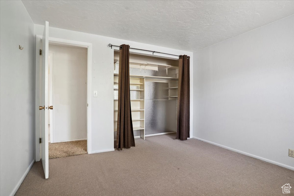 Unfurnished bedroom featuring a closet, baseboards, carpet flooring, and a textured ceiling