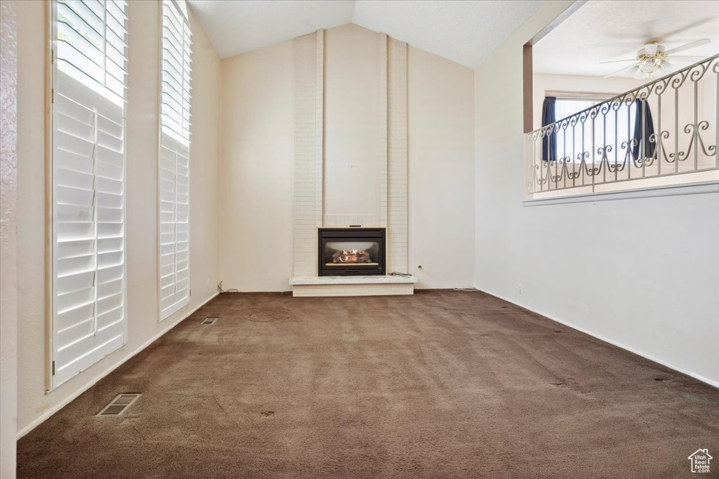 Unfurnished living room with a fireplace, plenty of natural light, carpet, and visible vents