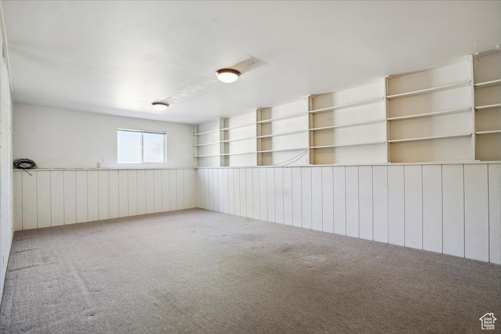 Carpeted spare room featuring wood walls