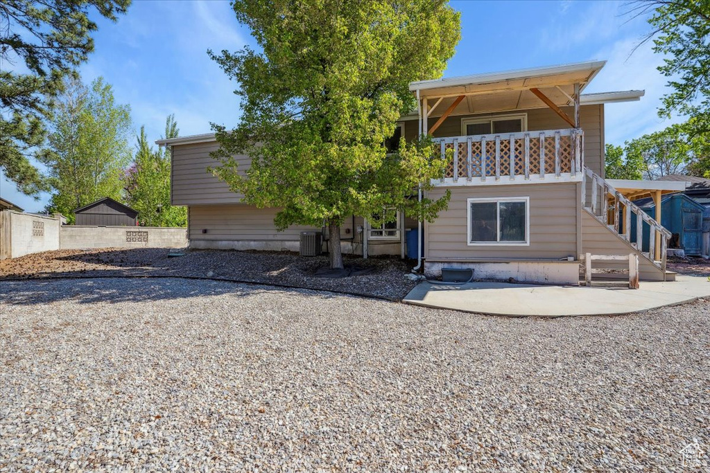 Rear view of property with stairway, central AC unit, and a patio area