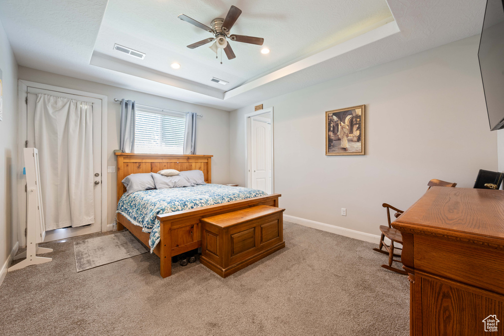 Bedroom featuring a raised ceiling, baseboards, light carpet, and visible vents