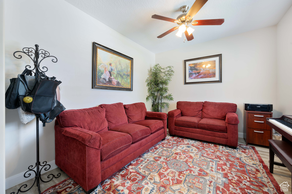 Living room featuring light wood-style floors, a ceiling fan, and baseboards