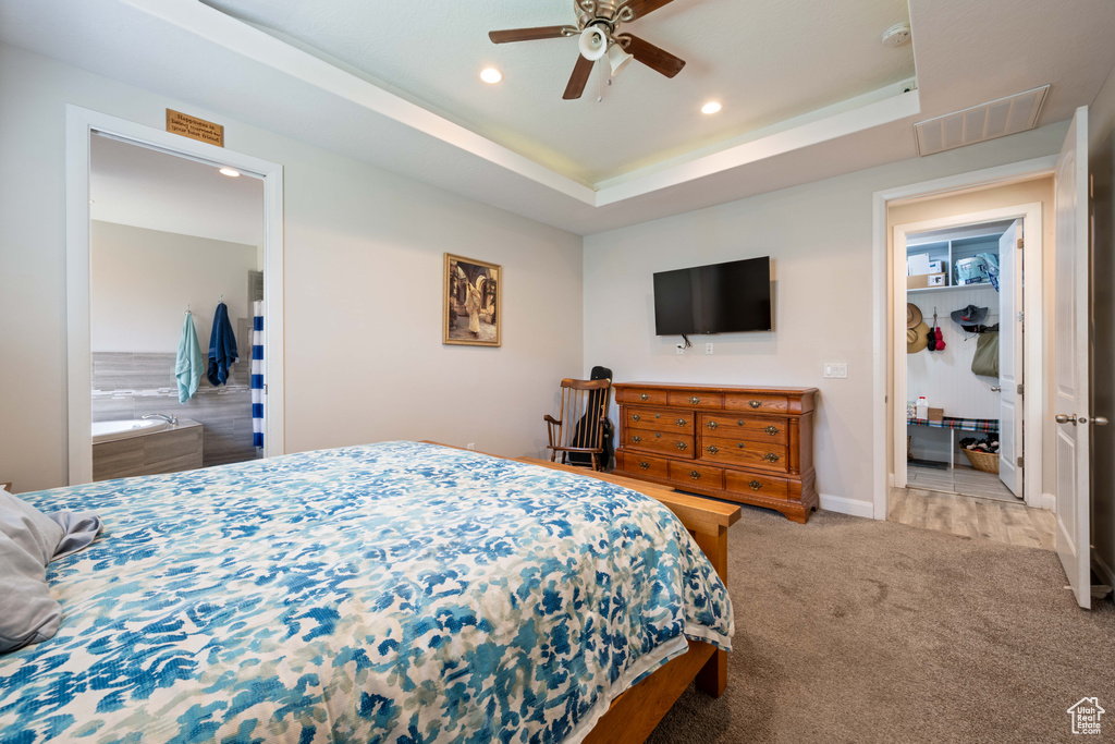 Carpeted bedroom with a raised ceiling, ceiling fan, recessed lighting, and visible vents