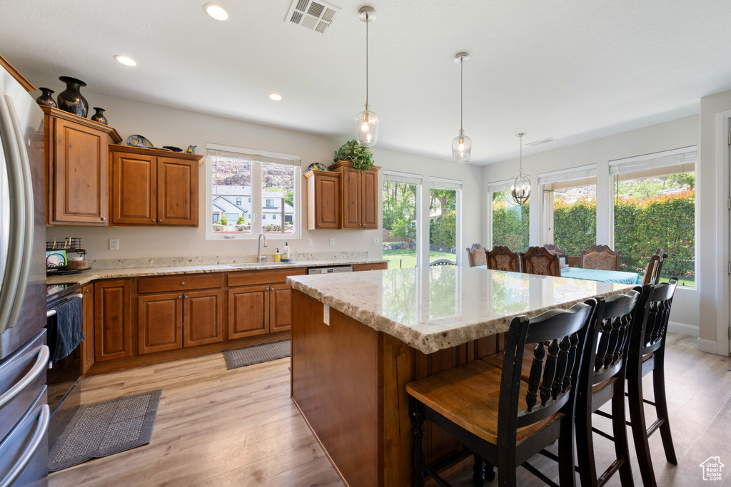 Kitchen with brown cabinets, visible vents, a kitchen island, and a sink