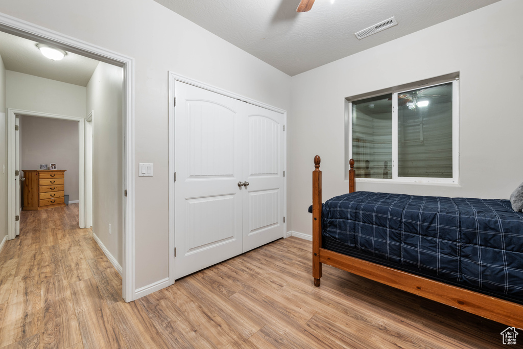 Bedroom featuring ceiling fan, visible vents, baseboards, a closet, and light wood finished floors