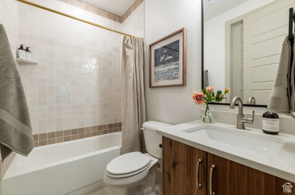 Bathroom featuring vanity, shower / bathtub combination with curtain, and toilet