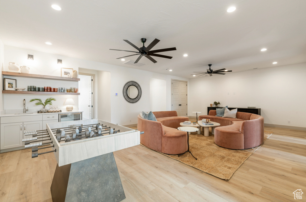Living room featuring ceiling fan, light wood finished floors, recessed lighting, and beverage cooler