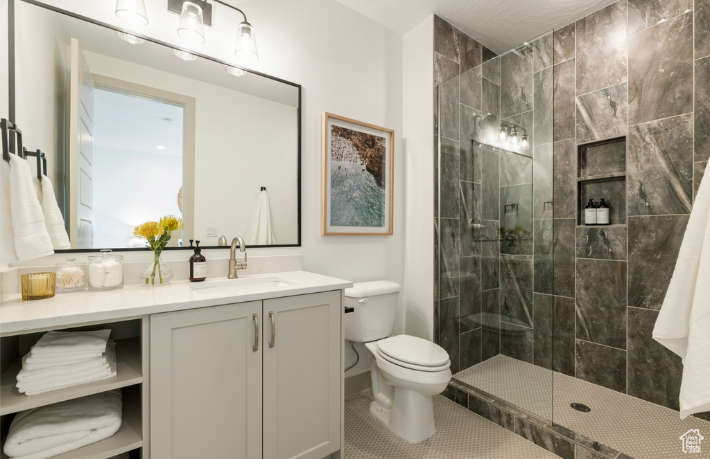 Bathroom featuring vanity, a walk in shower, tile patterned floors, and toilet