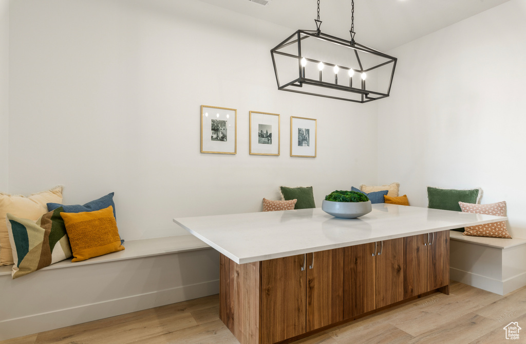 Dining room featuring baseboards, a chandelier, breakfast area, and light wood-style flooring