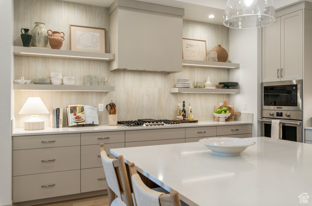 Kitchen featuring light countertops, stainless steel appliances, open shelves, and recessed lighting