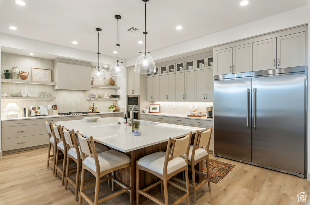 Kitchen featuring open shelves, appliances with stainless steel finishes, light countertops, decorative backsplash, and visible vents